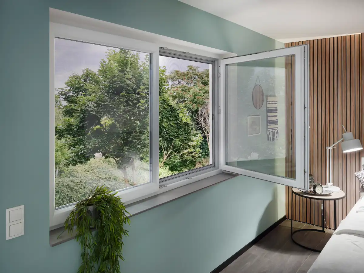 Offenes Fenster mit Blick auf grüne Bäume und modernes Schlafzimmer