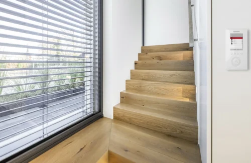 Innenansicht eines Raumes mit geöffneten Jalousien und einer Steuerungseinheit an der Wand