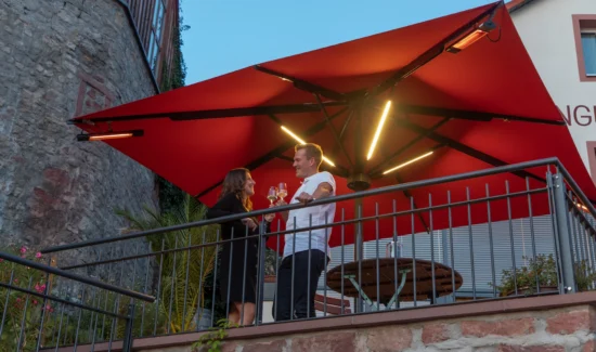 Abendliches Treffen unter einem beleuchteten roten Sonnenschirm