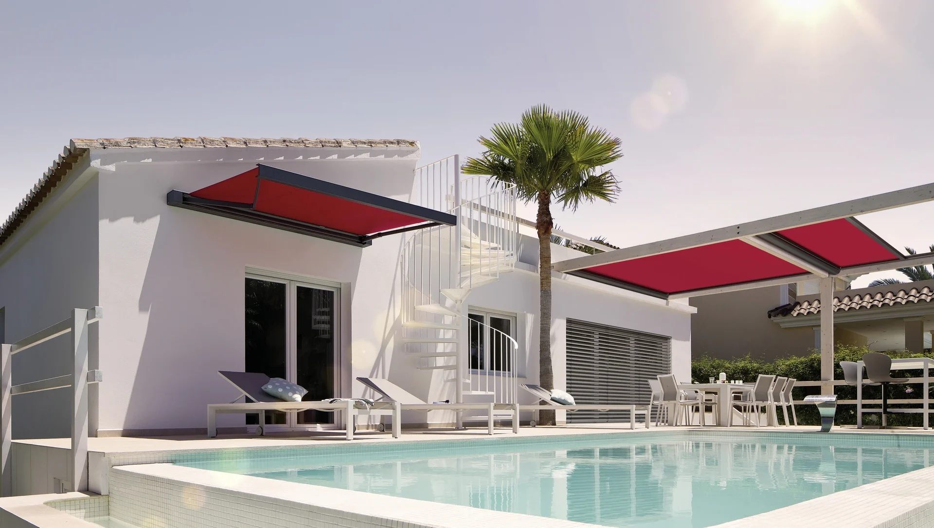 Moderne Villa mit Pool und roten Markisen bei Sonnenschein