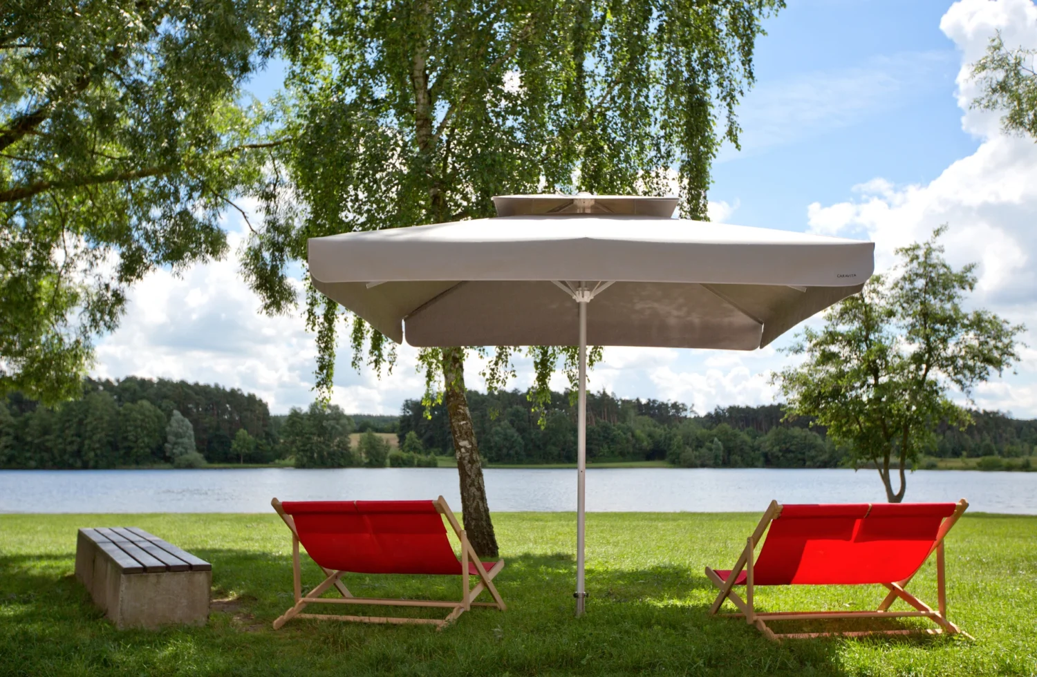 Roter Eckiger Sonnenschirm auf einer Liegewiese am See